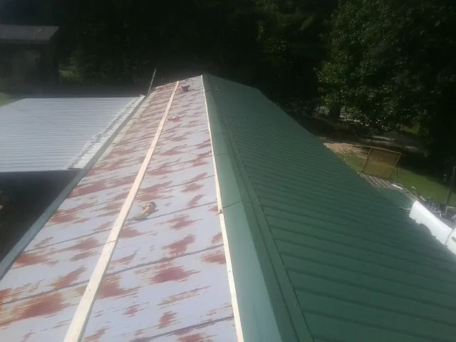 Old rusted panels beside newly installed green metal roofing — Wind Damage Roof Repair by Roofing Brothers in Widen