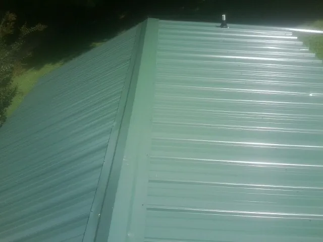 New green metal panels meeting at the ridge of a roof — Flat Roof Repair work by our crew in Widen