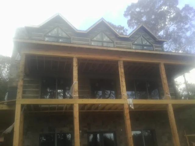Dormers and porch framing on a large log home under construction — Roof Coating work by our crew in Widen