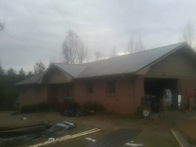 Gray metal roof on a stucco house with an attached garage in Widen