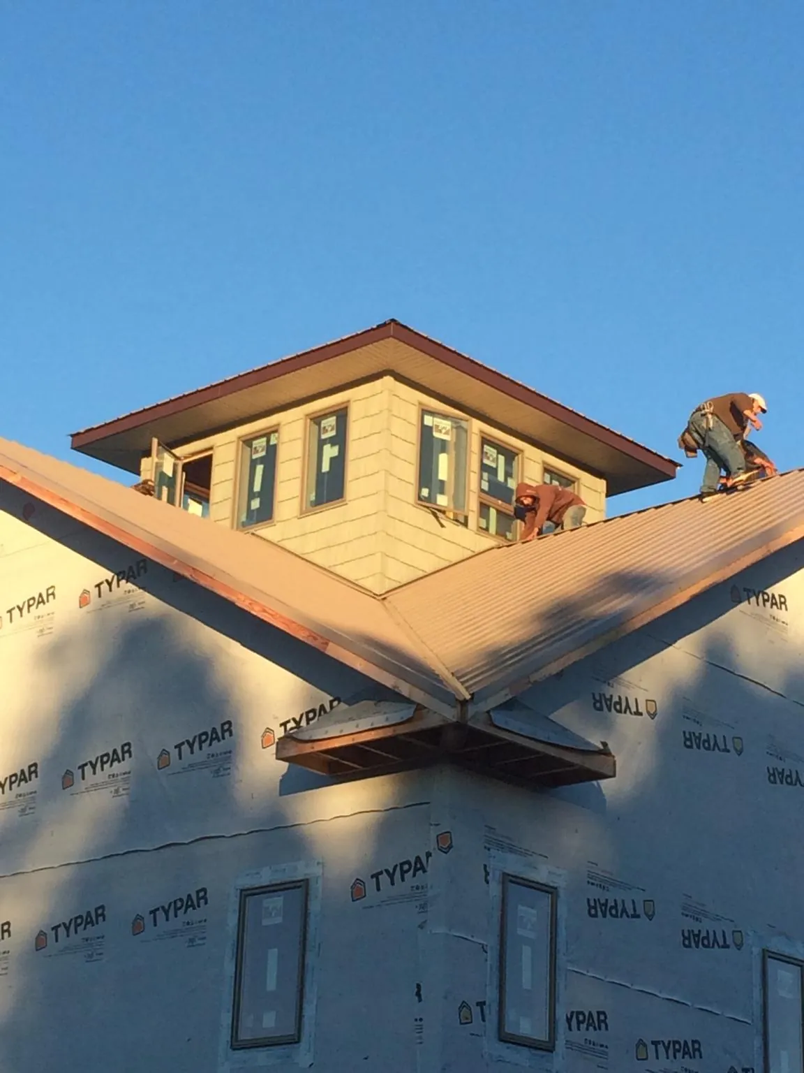 Roofers working around a rooftop cupola on a new metal roof at sunset — Roof Waterproofing in Widen by Roofing Brothers